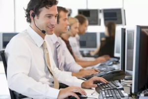 Brokerage service agents wearing headsets at a row of monitors
