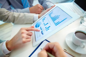 Hands pointing to bar charts on a tablet in an analysis meeting