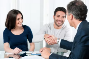 Smiling couple shaking hands with a banker across a desk
