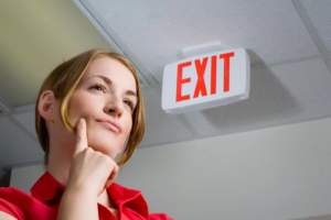 Woman thinking beneath an exit sign