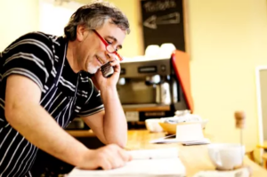 Cafe owner taking a phone call while reading paperwork