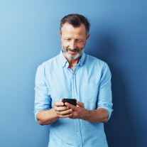Smiling man in a blue shirt looking at his phone