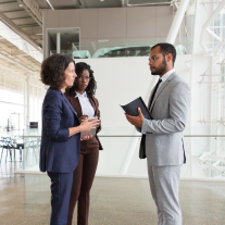 Three financial professionals talking in an office lobby